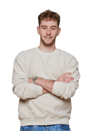 Smiling person in a light-colored sweater and jeans, arms crossed, against plain white background. Casual clothing and style.