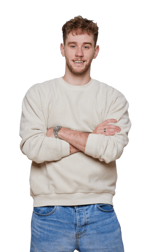 Smiling person in a light-colored sweater and jeans, arms crossed, against plain white background. Casual clothing and style.